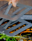 Metal grill chefs press being used on a grill with vegetables