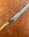 Serrated bread knife with wooden handle on a brown surface