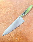 Chef's knife with a green handle on a brown surface