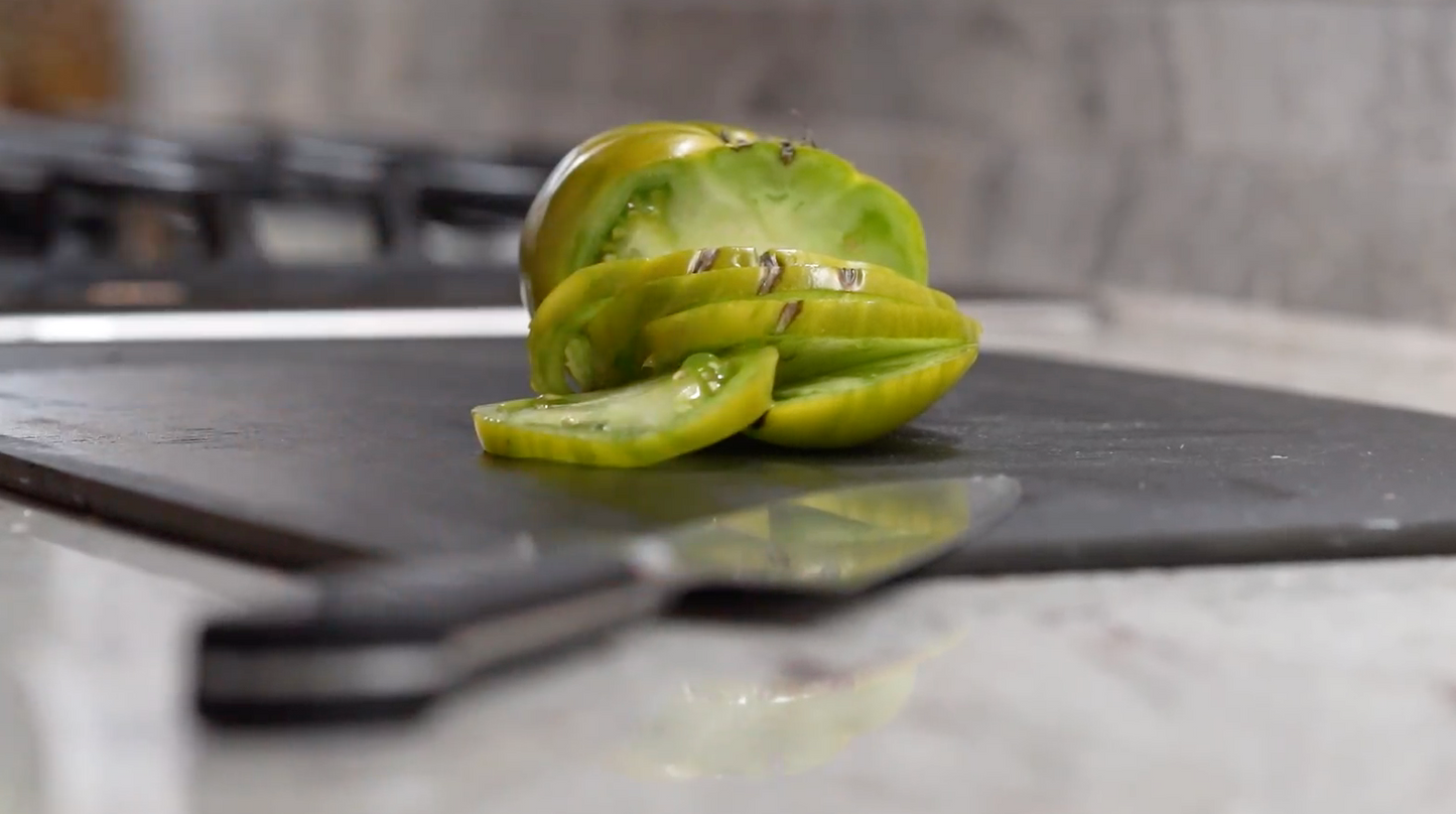 sharp kitchen knife with green tomato