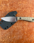 Knife with a black handle and silver blade on a brown leather surface Uinta