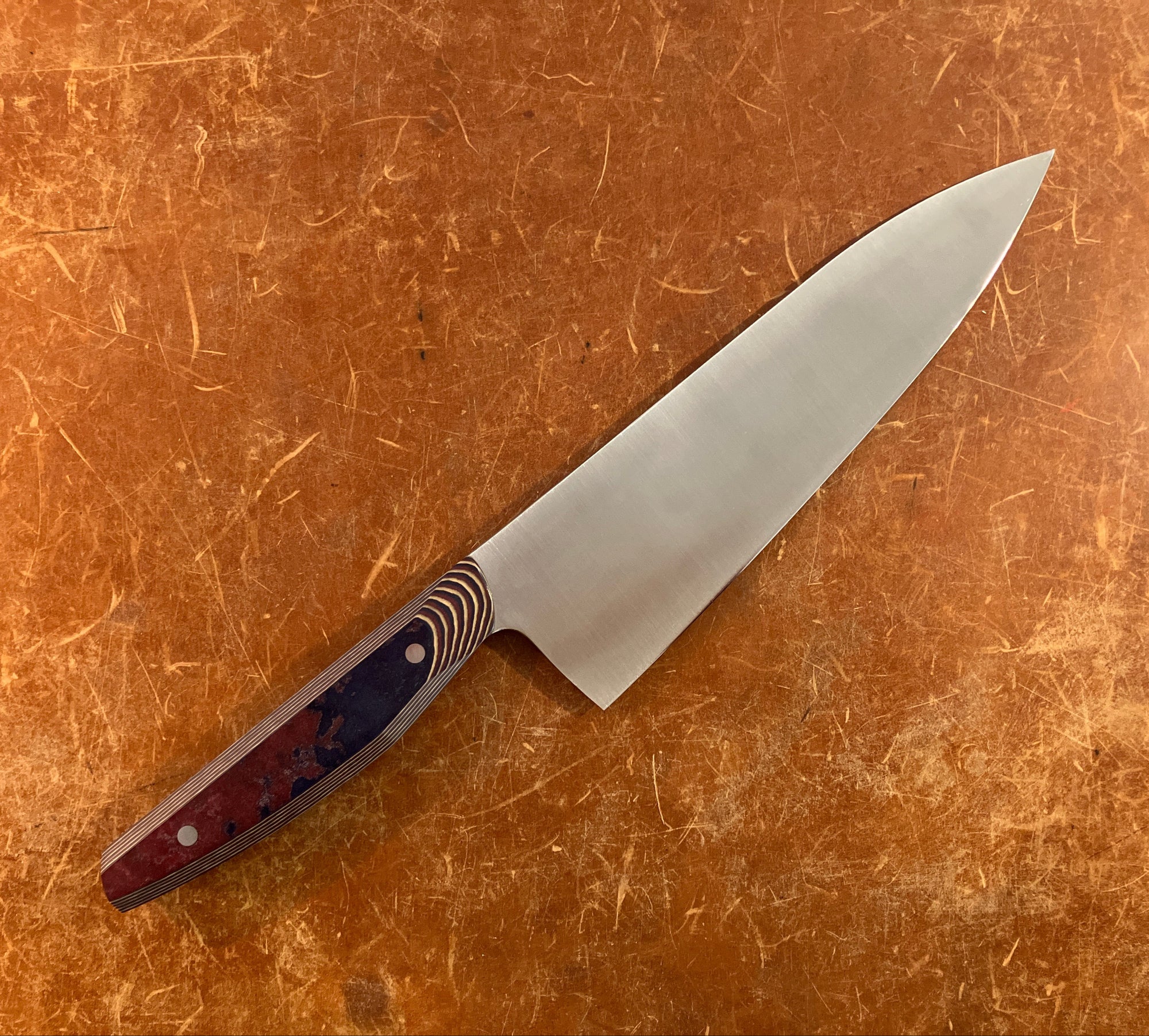 Chef&#39;s knife with a decorative handle on a brown surface