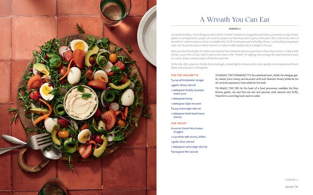 Platter of salad with a wreath shape on a red-tiled surface, next to a magazine page with text.