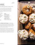 Carrot cake cupcakes with cream cheese frosting on a tray, alongside a recipe.