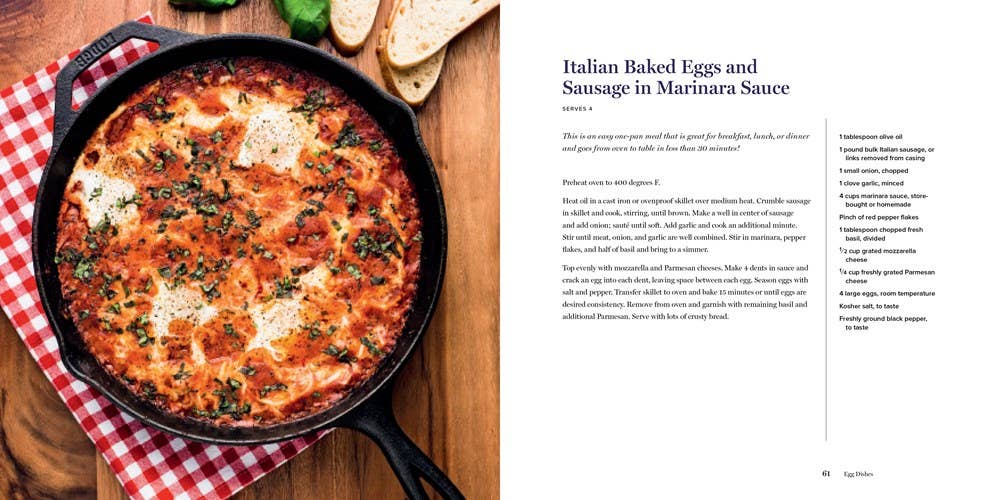 Skillet of Italian baked eggs and sausage with marinara sauce on a wooden board, next to a recipe card.