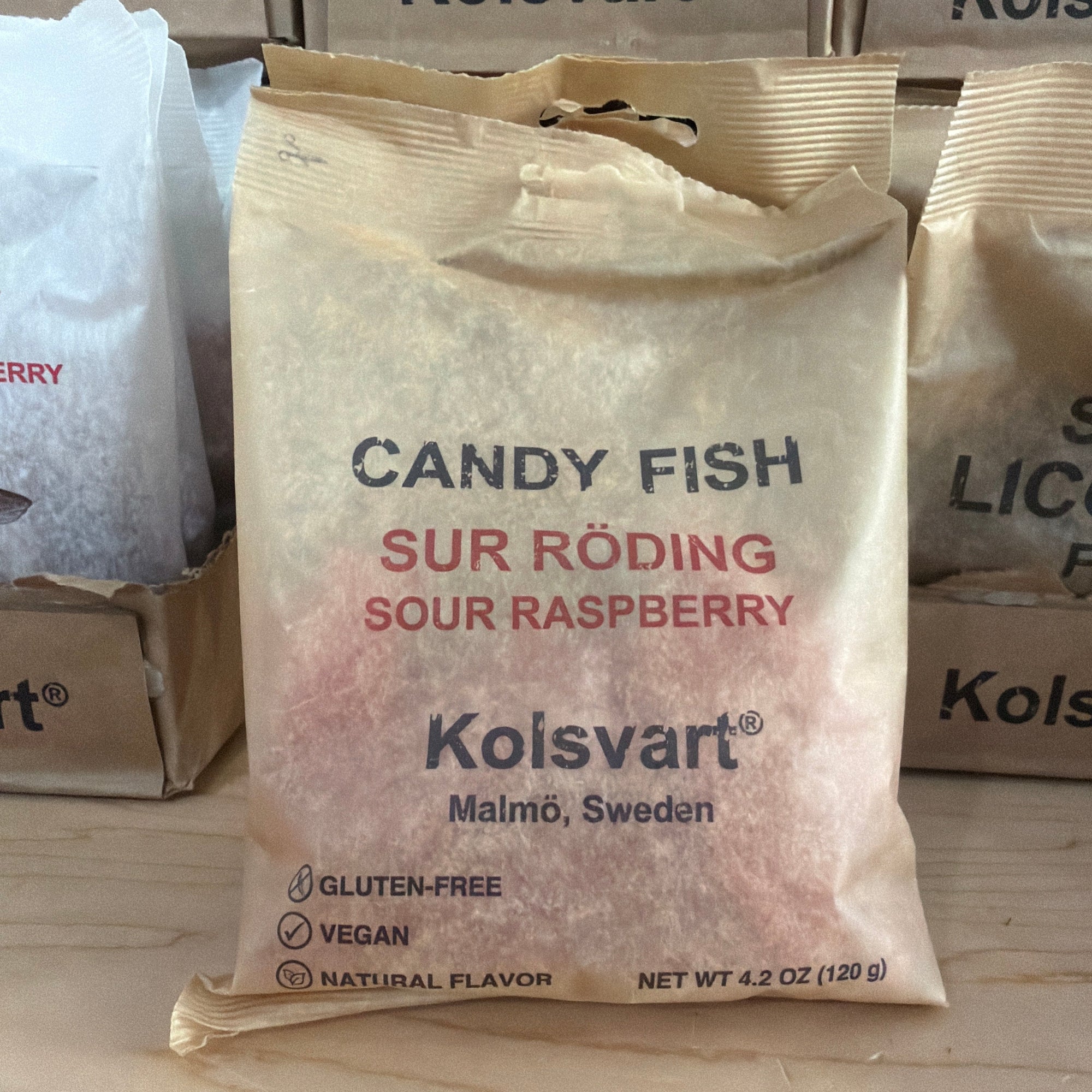 Kolsvart candy fish package on a wooden surface with boxes in the background