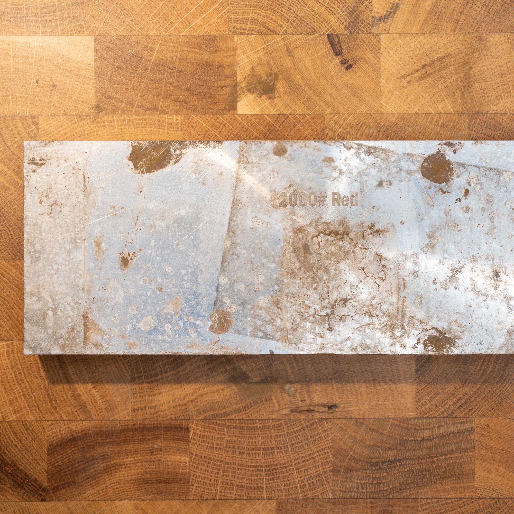 Rectangular metal block with text on a wooden surface 200 grit red diamond resin stone

