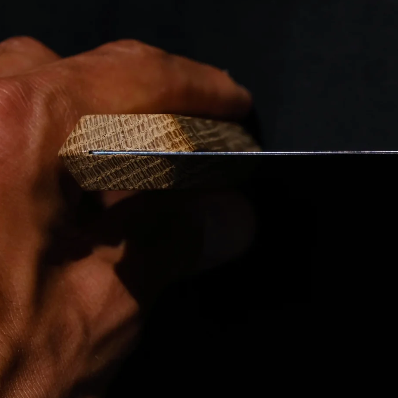 Hand holding a knife with a dark background