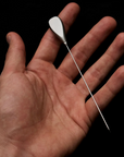Hand holding a thin metal rod with a white tip against a black background