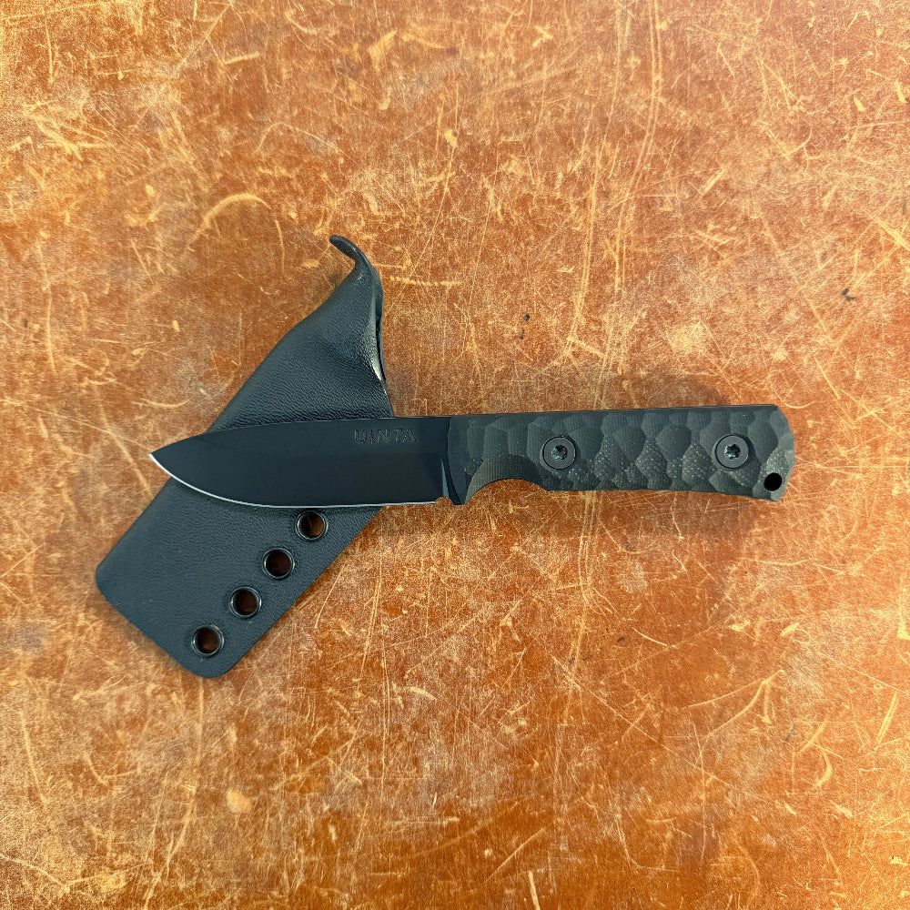 Black knife with sheath on a brown textured surface