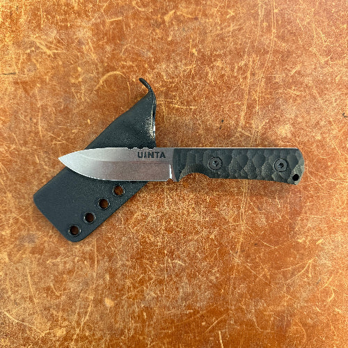 Knife with a black sheath on a brown surface Uinta
