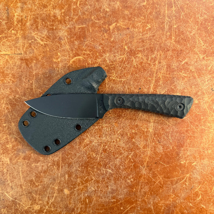 Black knife with sheath on a brown textured surface Uinta