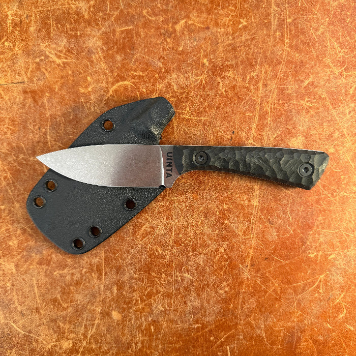 Knife with a black handle and silver blade on a brown surface  Uinta