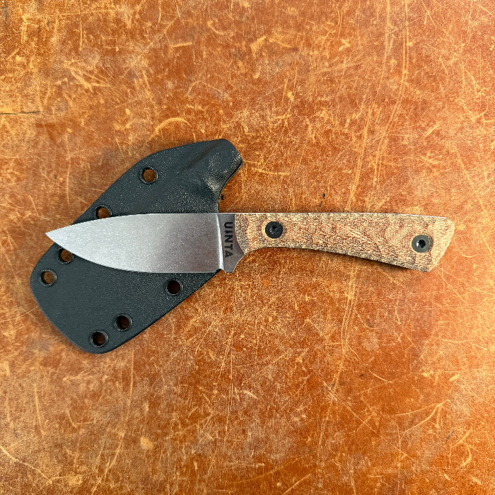 Folded knife with wooden handle and metal blade on a brown surface  Uinta